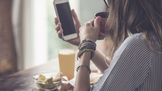Woman using cellphone and laptop inside house and drinking coffee - Small